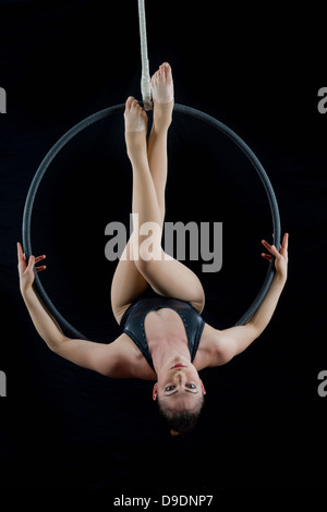 Aerialist performing on hoop in front of black background Stock Photo