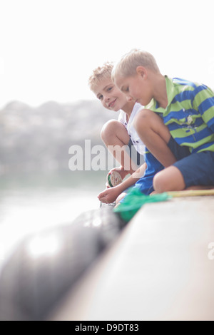 Close up of two young boys fishing on pier Stock Photo