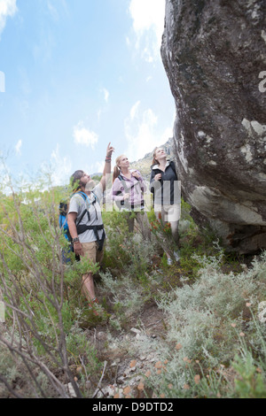 Young hikers looking up at large boulder Stock Photo