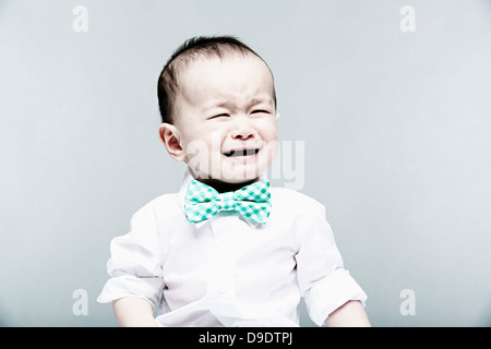 Portrait of baby boy wearing shirt and bow tie, crying Stock Photo