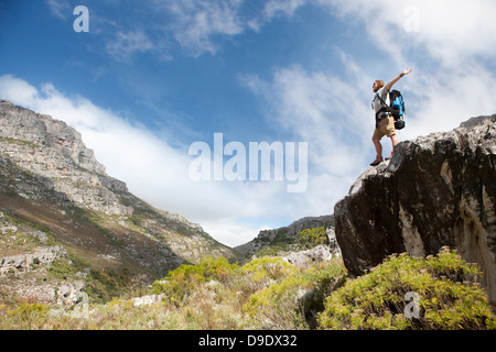 Male hiker standing on rock formation with arms outstretched Stock Photo