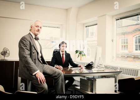 Young businessman at desk with senior man in office Stock Photo