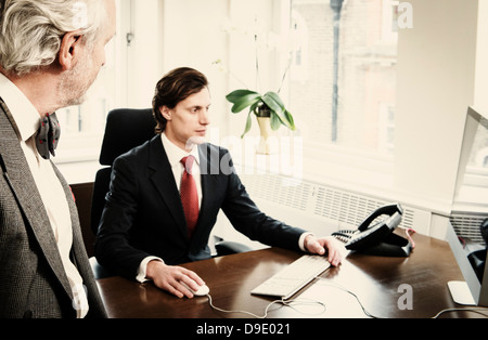 Young businessman at desk with senior man in office Stock Photo