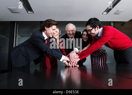 Business team putting their hands on top of each other at meeting table Stock Photo
