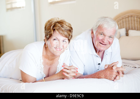 happy senior couple lying on bed Stock Photo