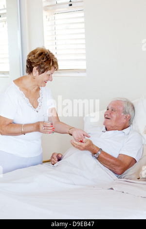 caring senior wife giving medicine to ill husband Stock Photo