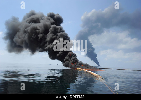 Dark clouds of smoke and fire emerge as oil burns during a controlled fire in the Gulf of Mexico. Stock Photo