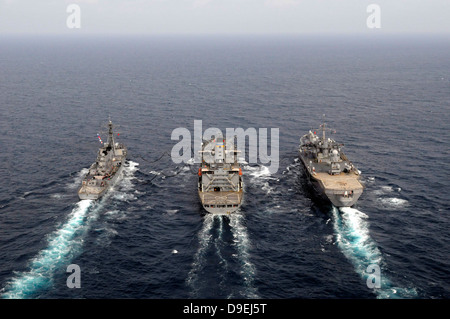 Military ships conduct an underway replenishment in the Pacific Ocean. Stock Photo