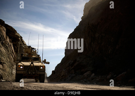 A MRAP vehicle drives through the mountains of Afghanistan. Stock Photo
