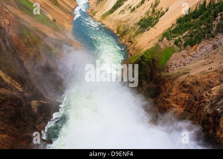 Mist billows from brink of Lower Falls into Yellowstone River running through Grand Canyon of Yellowstone Stock Photo
