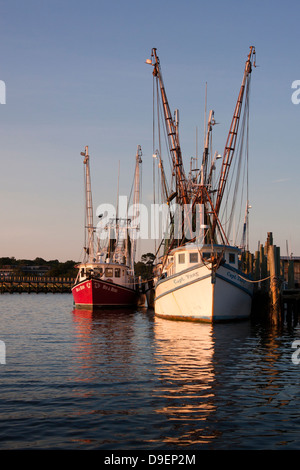 The sun sets on the active waterfront along Shem Creek, Mount Pleasant, South Carolina, USA bathing it in a warm glow.