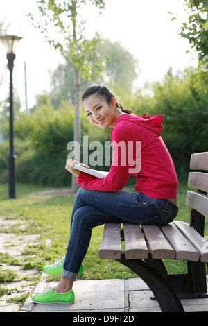 young woman reading book on a bench Stock Photo