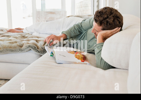 Man lying on the bed and reading a magazine Stock Photo