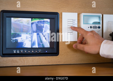 Person's hand pushing buttons for a security surveillance system at home Stock Photo