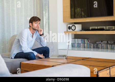 Man sitting in a living room and thinking Stock Photo