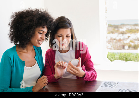 Friends using a mobile phone and smiling Stock Photo
