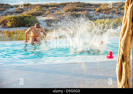 Two male friends enjoying in a swimming pool on the beach Stock Photo