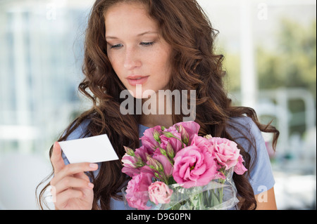 Woman reading a card with bouquet of flowers Stock Photo