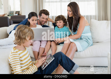 Boy using a digital tablet with his family looking at a laptop Stock Photo
