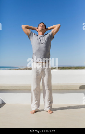 Man standing with hands behind head Stock Photo