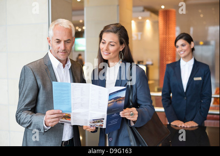 Business couple reading a brochure in front of a hotel reception counter Stock Photo