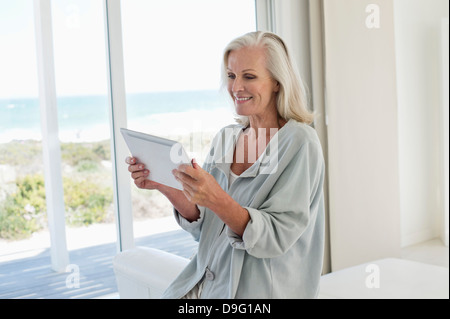 Woman using a digital tablet and smiling at home Stock Photo