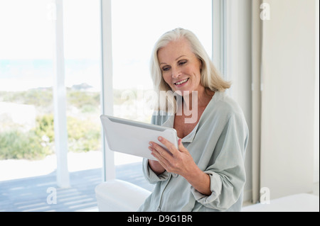 Woman using a digital tablet and smiling at home Stock Photo