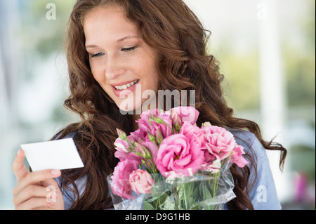 Woman reading a card with bouquet of flowers Stock Photo