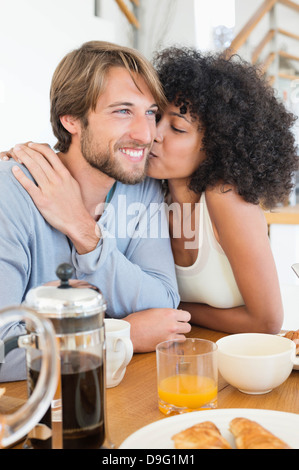 Woman kissing her husband at a dining table Stock Photo