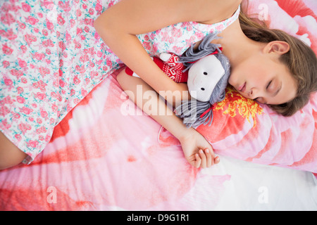 Girl sleeping on the bed with a rag doll