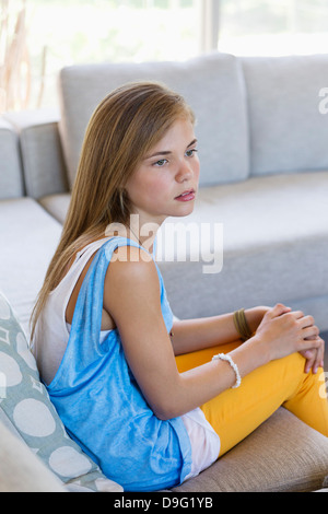 Girl sitting on a couch and looking upset Stock Photo