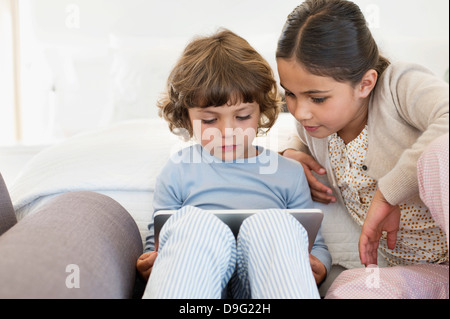 Girl looking at her brother using a digital tablet Stock Photo