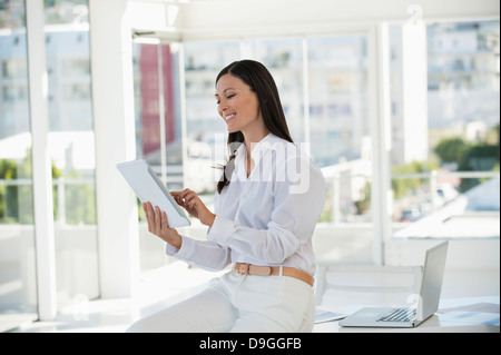 Businesswoman holding a digital tablet and smiling in an office Stock Photo