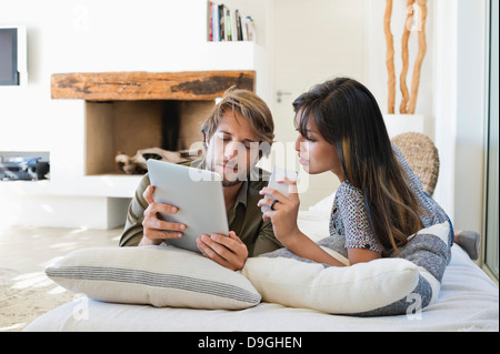 Couple lying on the bed and using electronic gadgets Stock Photo