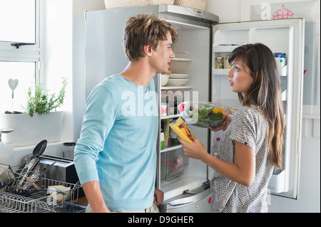 Couple talking in front of a refrigerator in the kitchen Stock Photo