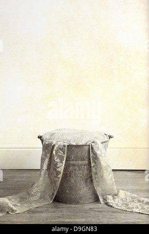 A rusty metal bucket filled with cloth and lace material, placed on a wooden floor Stock Photo