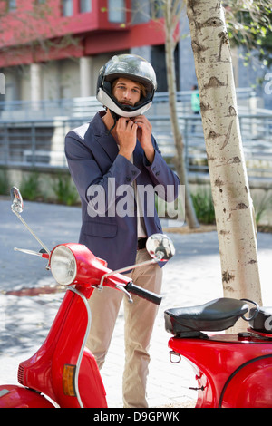 Man standing near a scooter on a street Stock Photo