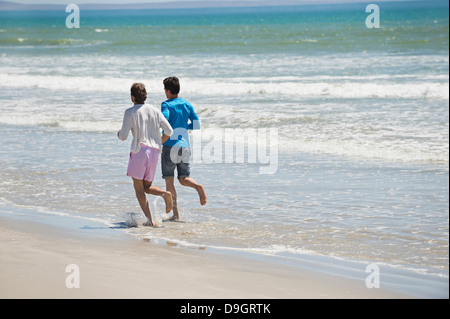 Two men running on the beach Stock Photo
