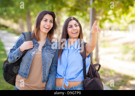 Teen Twin Sisters Walking Together Wearing Backpacks Outside. Stock Photo