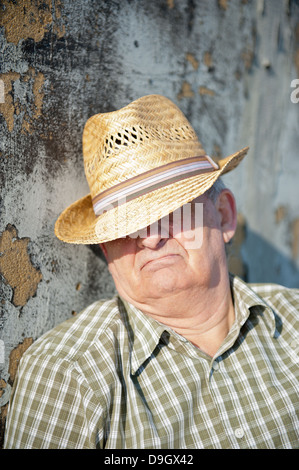 Senior man taking a siesta in the Mediterranean sunshine with his straw hat shielding his eyes. Stock Photo