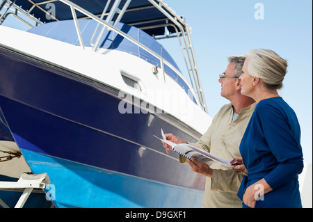 Couple standing near a yacht with a brochure Stock Photo
