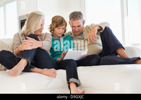 Boy using a digital tablet with his grandparents on a couch Stock Photo