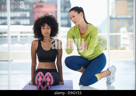 Woman practicing yoga with the help of an instructor Stock Photo