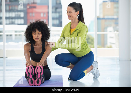 Woman practicing yoga with the help of an instructor Stock Photo