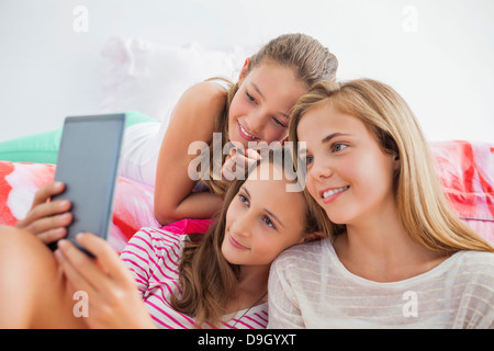 Three girls using a digital tablet at a slumber party Stock Photo