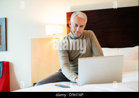 Man using a laptop in a hotel room Stock Photo