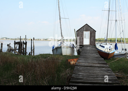 Three yachts at low tide moored to old wooden jetty at historic Skippool Creek Thornton Lancashire UK. Stock Photo