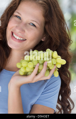 Portrait of a woman holding a bunch of grapes and smiling Stock Photo