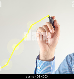 Businessman drawing rising graph with yellow marker pen on the screen Stock Photo