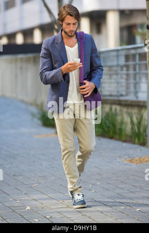Man walking on a street using a mobile phone Stock Photo